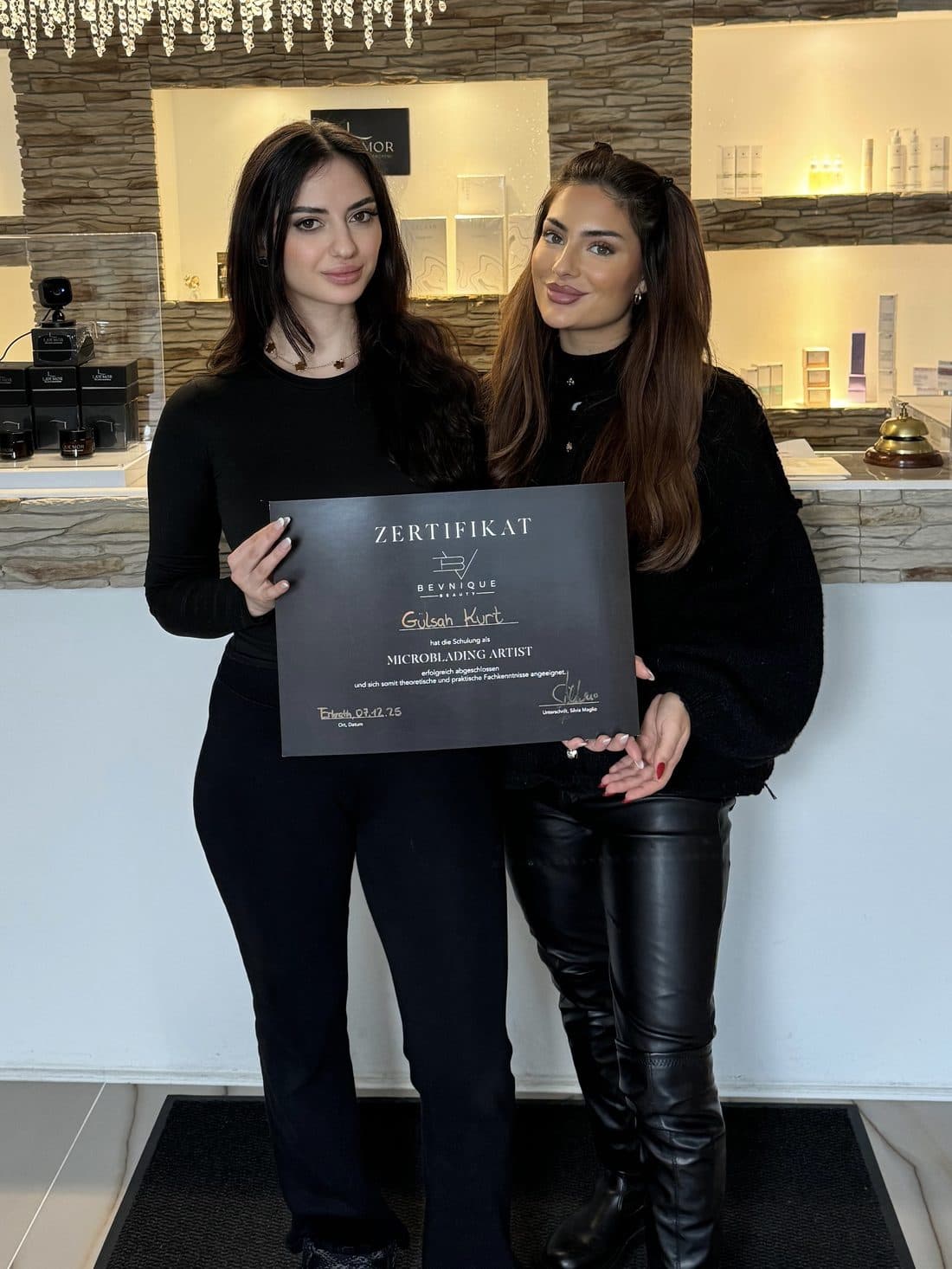 Zwei Absolventinnen mit ihren Zertifikaten der Bevnique Beauty Academy